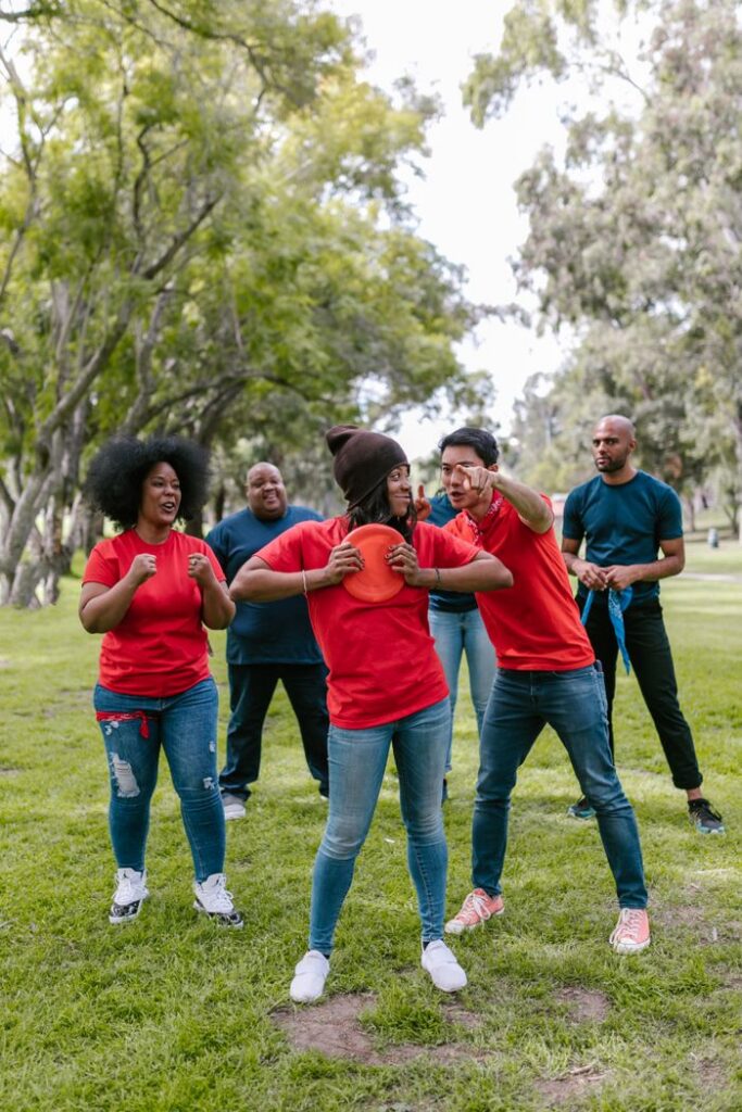 Group of adults enjoying a fun team-building exercise in a lush park setting.