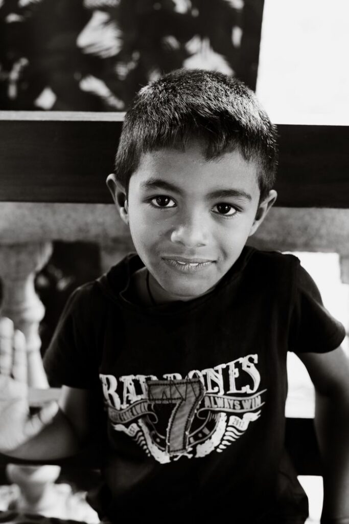 Black and white portrait of a smiling boy in a casual black shirt indoors.